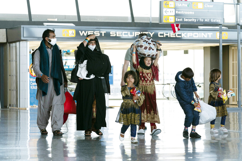 Families evacuated from Kabul, Afghanistan, walk through the terminal before boarding a bus after they arrived at Washington Dulles International Airport, in Chantilly, Va., on Monday, Aug. 30, 2021. (AP Photo/Jose Luis Magana)