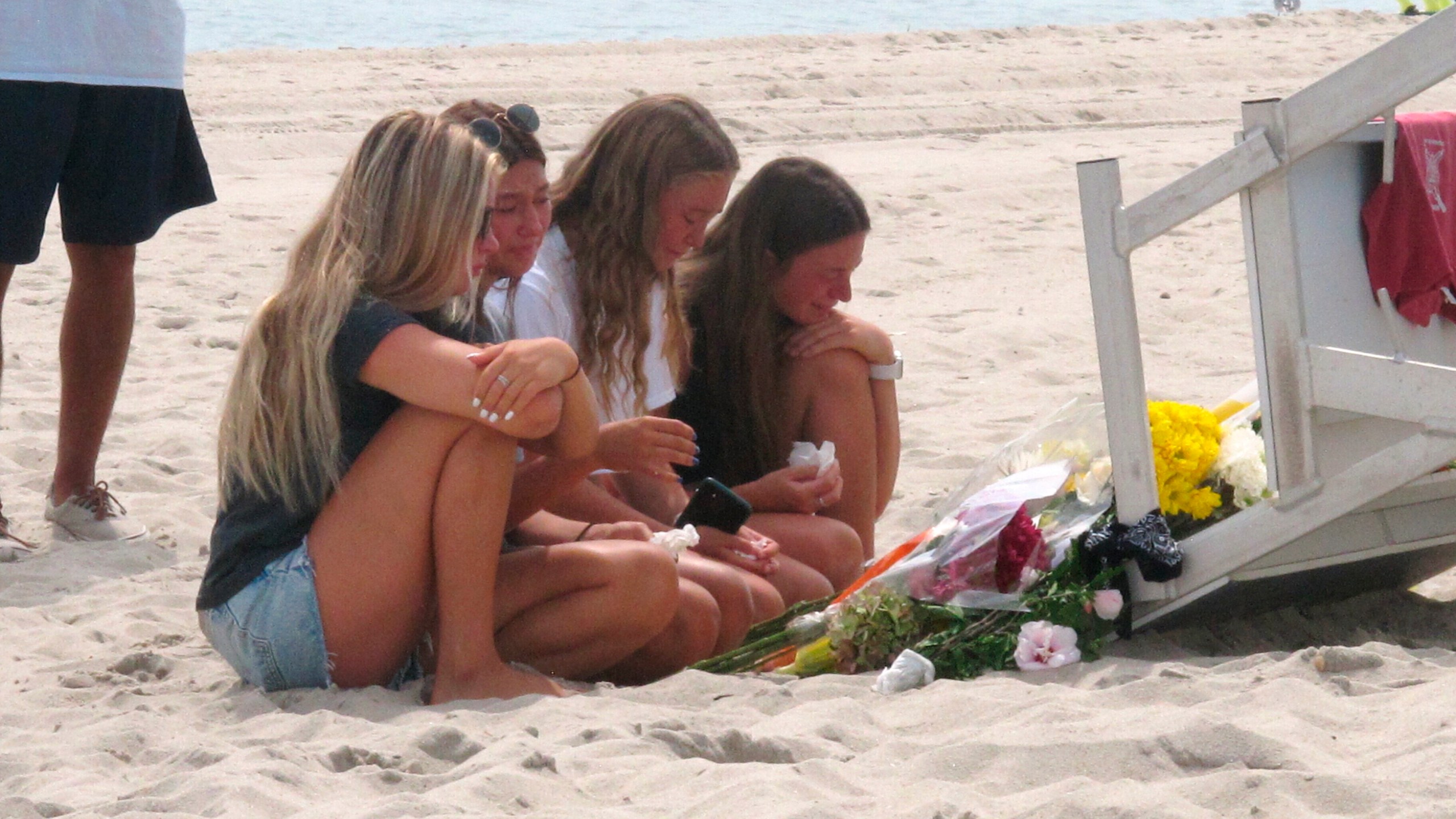 Friends and fellow lifeguards cry at the foot of a lifeguard stand in Berkeley Township, N.J., on Aug. 31, 2021, a day after 19-year-old lifeguard Keith Pinto was killed by lightning there. (Wayne Parry / Associated Press)