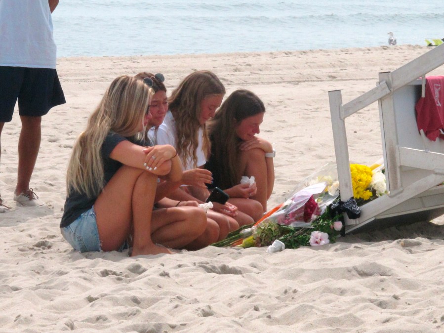 Friends and fellow lifeguards cry at the foot of a lifeguard stand in Berkeley Township, N.J., on Aug. 31, 2021, a day after 19-year-old lifeguard Keith Pinto was killed by lightning there. (Wayne Parry / Associated Press)