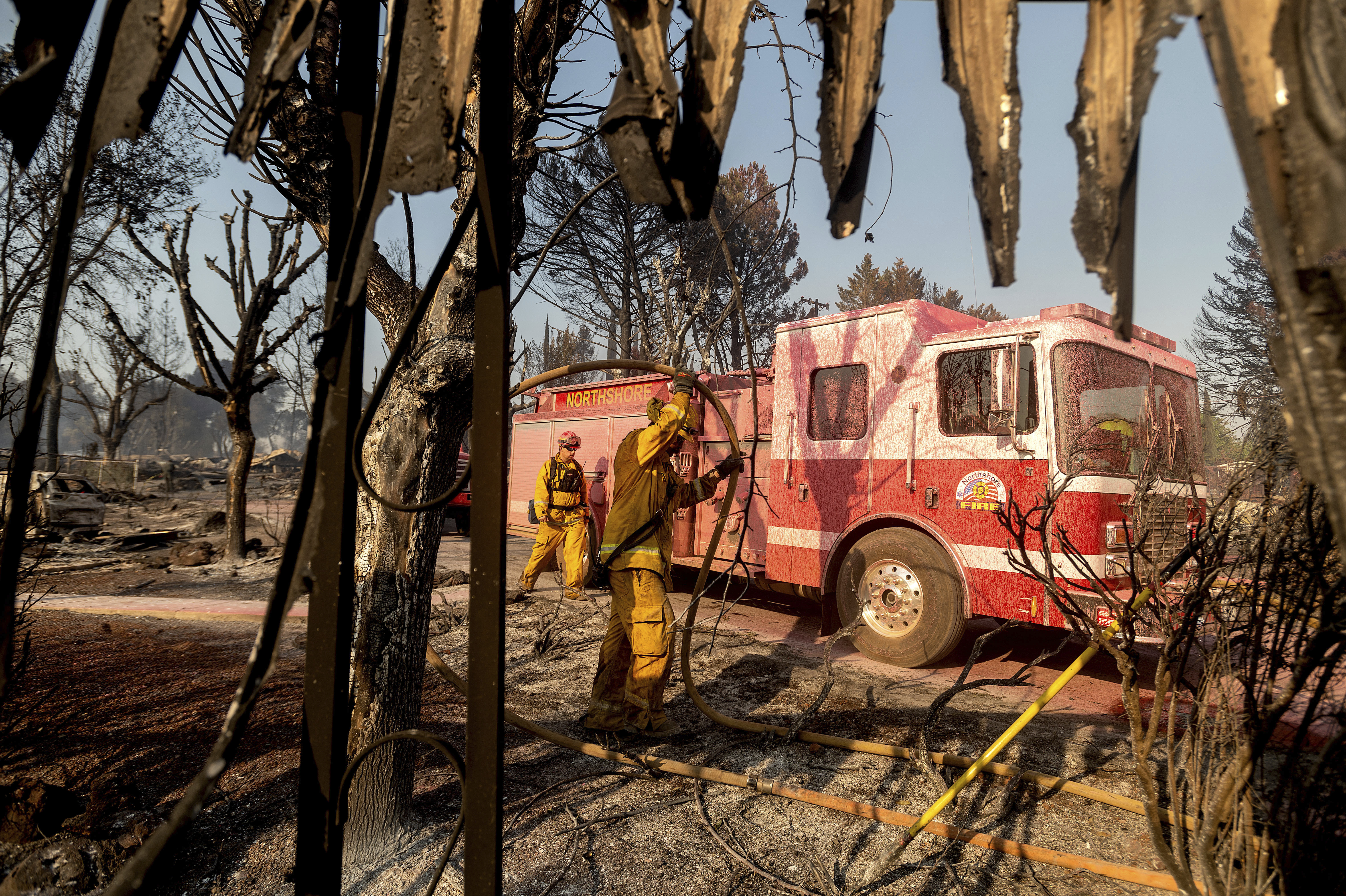 Firefighters mop up at Cache Creek Mobile Home Estates where the Cache Fire leveled dozens of residences on Wednesday, Aug. 18, 2021, in Clearlake, Calif. (AP Photo/Noah Berger)