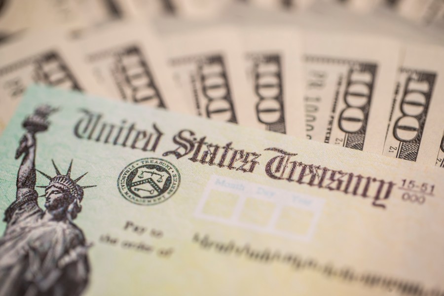 A U.S. Treasury check and $100 bills are seen in a file photo. (iStock/Getty Images Plus)