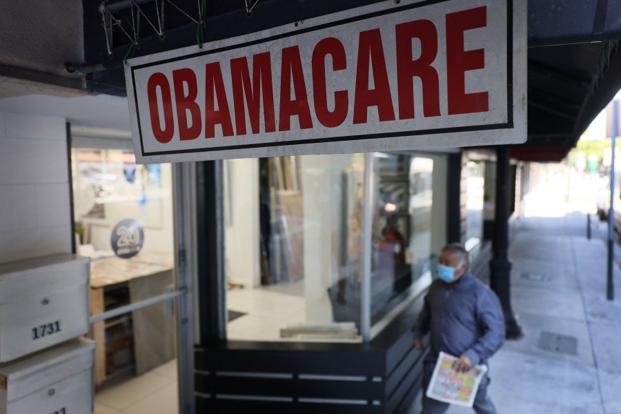 A pedestrian walks past an insurance agency offering plans under the Affordable Care Act on Jan. 28, 2021 in Miami, Florida. (Joe Raedle/Getty Images)