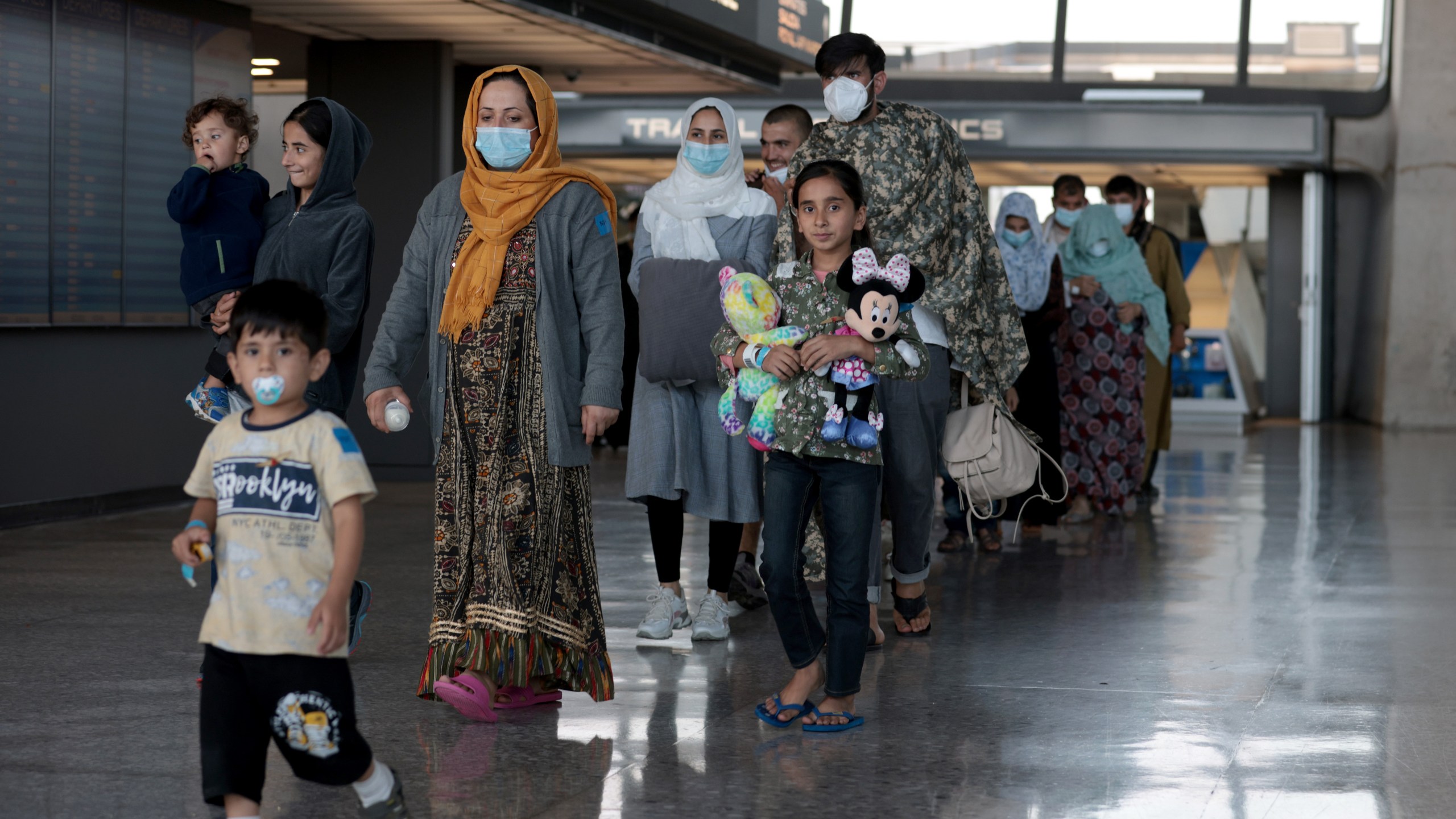 A family evacuated from Afghanistan is led through the arrival terminal at the Dulles International Airport to board a bus that will take them to a refugee processing center on Aug. 25, 2021 in Dulles, Virginia. (Anna Moneymaker/Getty Images)