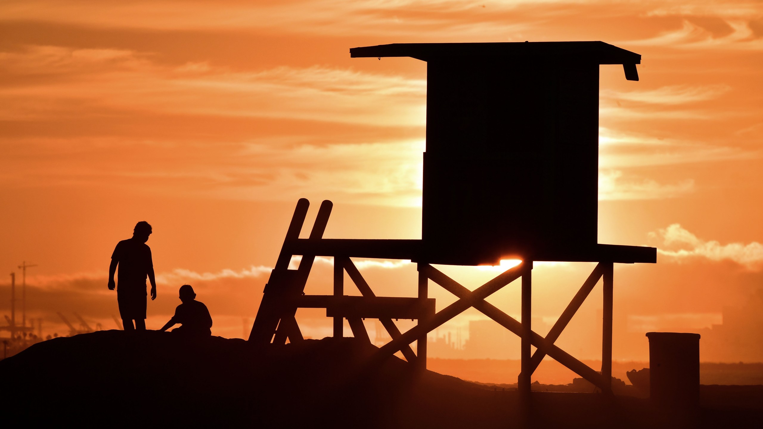 Children play beside a lifeguard tower as sunset approaches at Sunset Beach in Huntington Beach on July 21, 2018. (Frederic J. Brown/AFP via Getty Images)