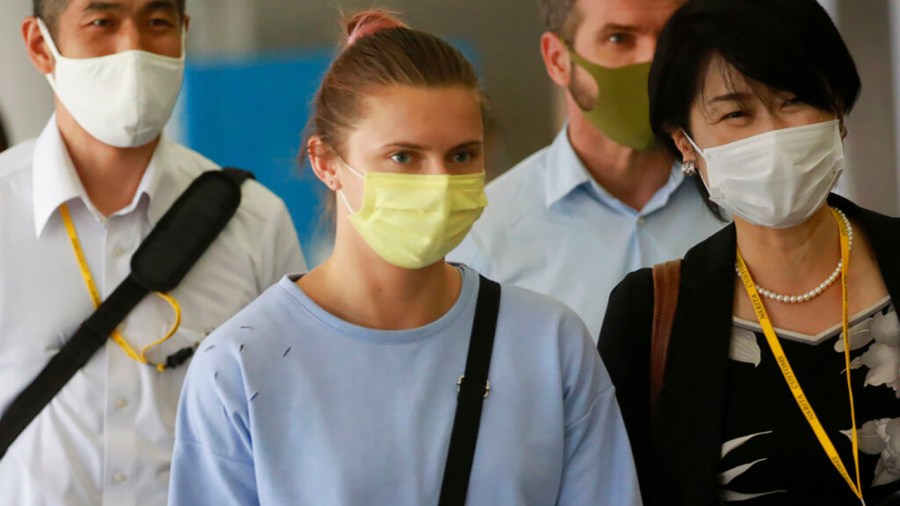 Belarusian Olympic sprinter Krystsina Tsimanouskaya, center, arrives at Narita International Airport in Narita, east of Tokyo Wednesday, Aug. 4, 2021. Tsimanouskaya plans to seek refuge in Europe after accusing team officials of trying to force her to leave the Tokyo Games early. (AP Photo/Koji Sasahara)