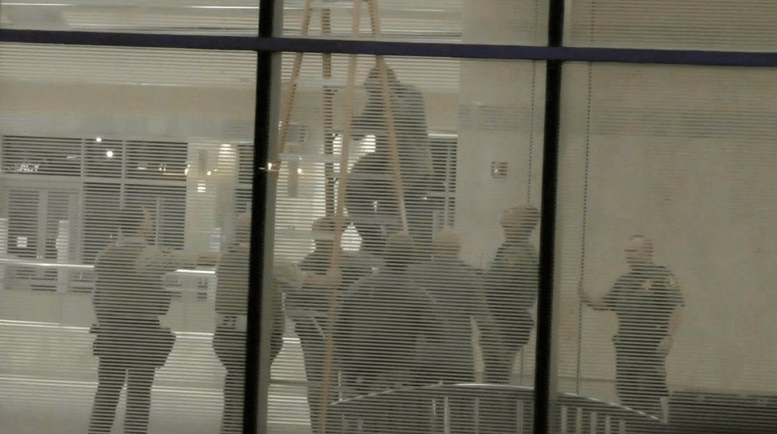 A man climbs down from a ceiling at Johne Wayne Airport seen during a security incident that prompted evacuations on Aug. 20, 2021. (O.C. Hawk)