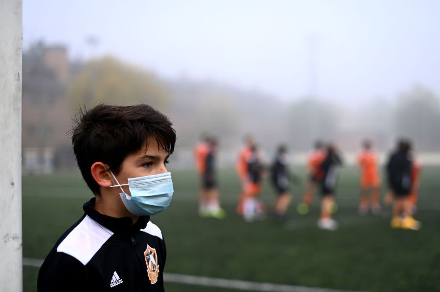 A boy wearing a face mask to protect against the spread of the novel coronavirus attends a football match with his team of Football Player Academy (FPA) Las Rozas in Las Rozas, outside Madrid, on Oct. 24, 2020. (Gabriel Bouys / AFP)