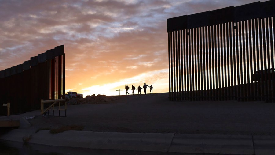 In this June 10, 2021 file photo, a pair of migrant families from Brazil pass through a gap in the border wall to reach the United States after crossing from Mexico to Yuma, Ariz., to seek asylum. (AP Photo/Eugene Garcia, File)