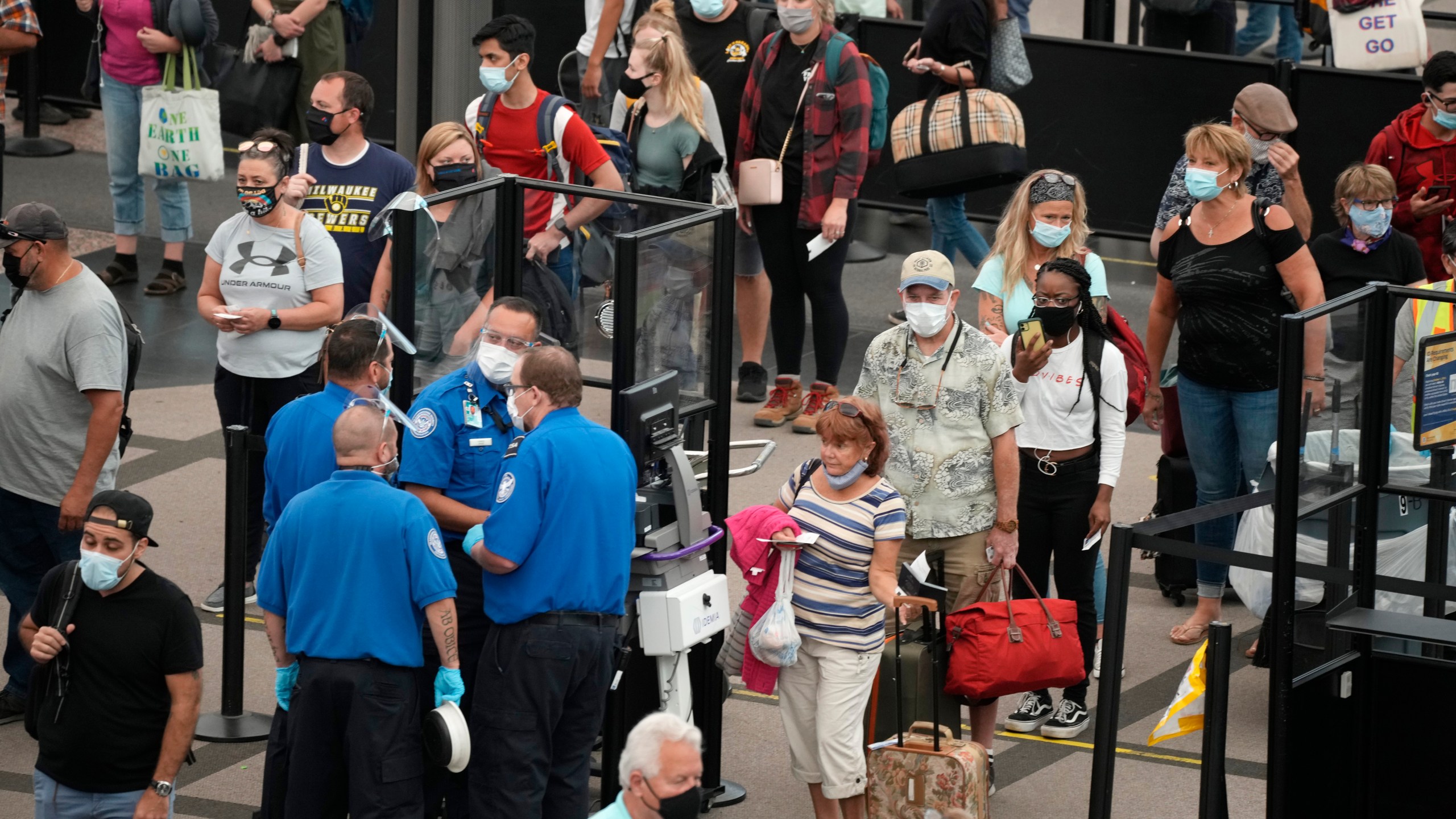 Travelers wear face coverings in the line for the south north security checkpoint in the main terminal of Denver International Airport Tuesday, Aug. 24, 2021, in Denver. Two months after the Sept. 11, 2001 attacks, President George W. Bush signed legislation creating the Transportation Security Administration, a force of federal airport screeners that replaced the private companies that airlines were hiring to handle security. (AP Photo/David Zalubowski)