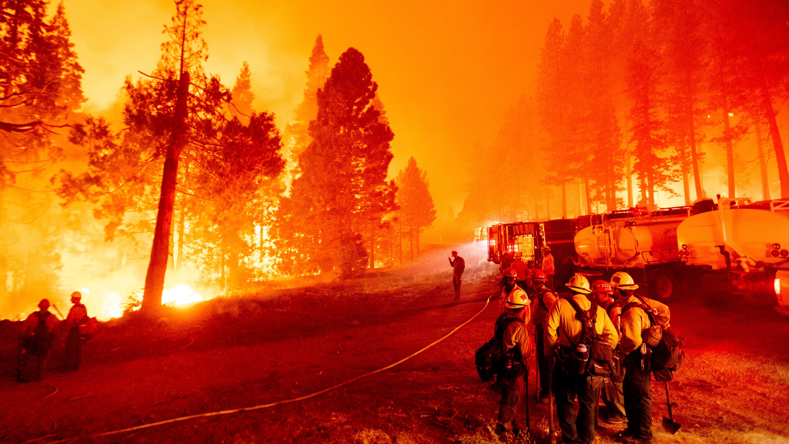 In this Thursday, Aug. 26, 2021 file photo, the Caldor Fire burns along both sides of Highway 50 as firefighters work to stop its eastward spread in Eldorado National Forest, Calif.. Last week, managers overseeing the fight against the massive wildfire scorching California's Lake Tahoe region thought they could have it contained by the start of this week. Instead, on Monday, Aug. 30, 2021, the Caldor Fire crested the Sierra Nevada, forcing the unprecedented evacuation of all 22,000 residents of South Lake Tahoe. (AP Photo/Noah Berger, File)