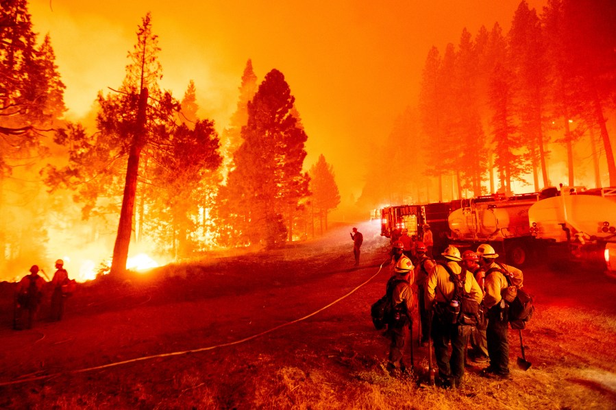 In this Thursday, Aug. 26, 2021 file photo, the Caldor Fire burns along both sides of Highway 50 as firefighters work to stop its eastward spread in Eldorado National Forest, Calif.. Last week, managers overseeing the fight against the massive wildfire scorching California's Lake Tahoe region thought they could have it contained by the start of this week. Instead, on Monday, Aug. 30, 2021, the Caldor Fire crested the Sierra Nevada, forcing the unprecedented evacuation of all 22,000 residents of South Lake Tahoe. (AP Photo/Noah Berger, File)