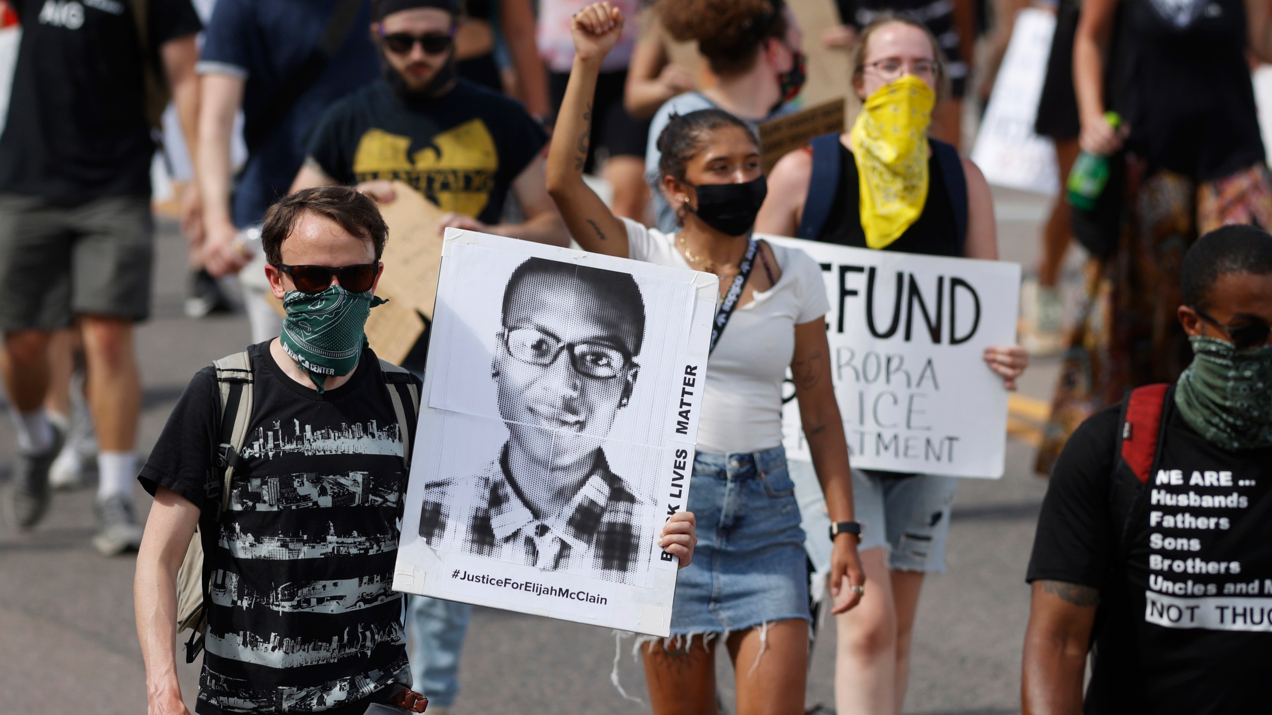 In this June 27, 2020 file photo demonstrators carry placards as they walk down Sable Boulevard during a rally and march over the death of Elijah McClain in Aurora, Colo. (David Zalubowski/Associated Press)