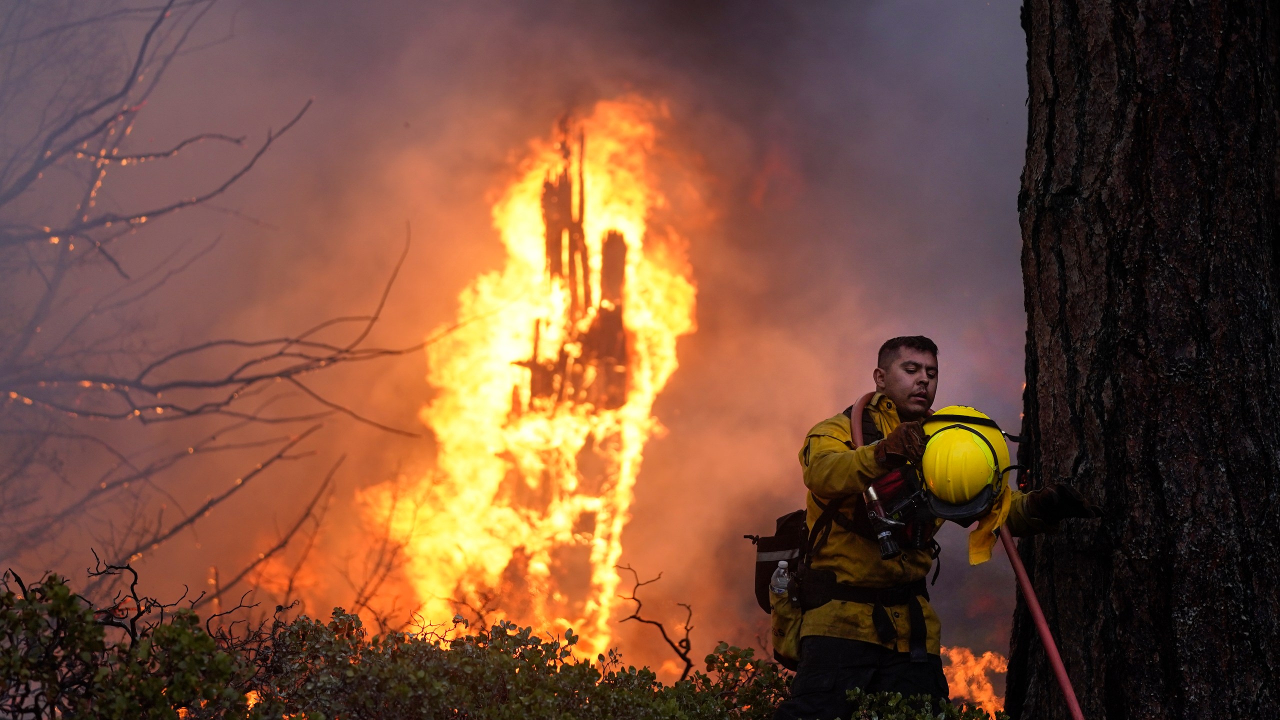 Firefighter Elroy Valadez adjusts his helmet while trying to put out a spot fire from the Caldor Fire burning along Highway 89 near South Lake Tahoe, Calif., Thursday, Sept. 2, 2021. (AP Photo/Jae C. Hong)