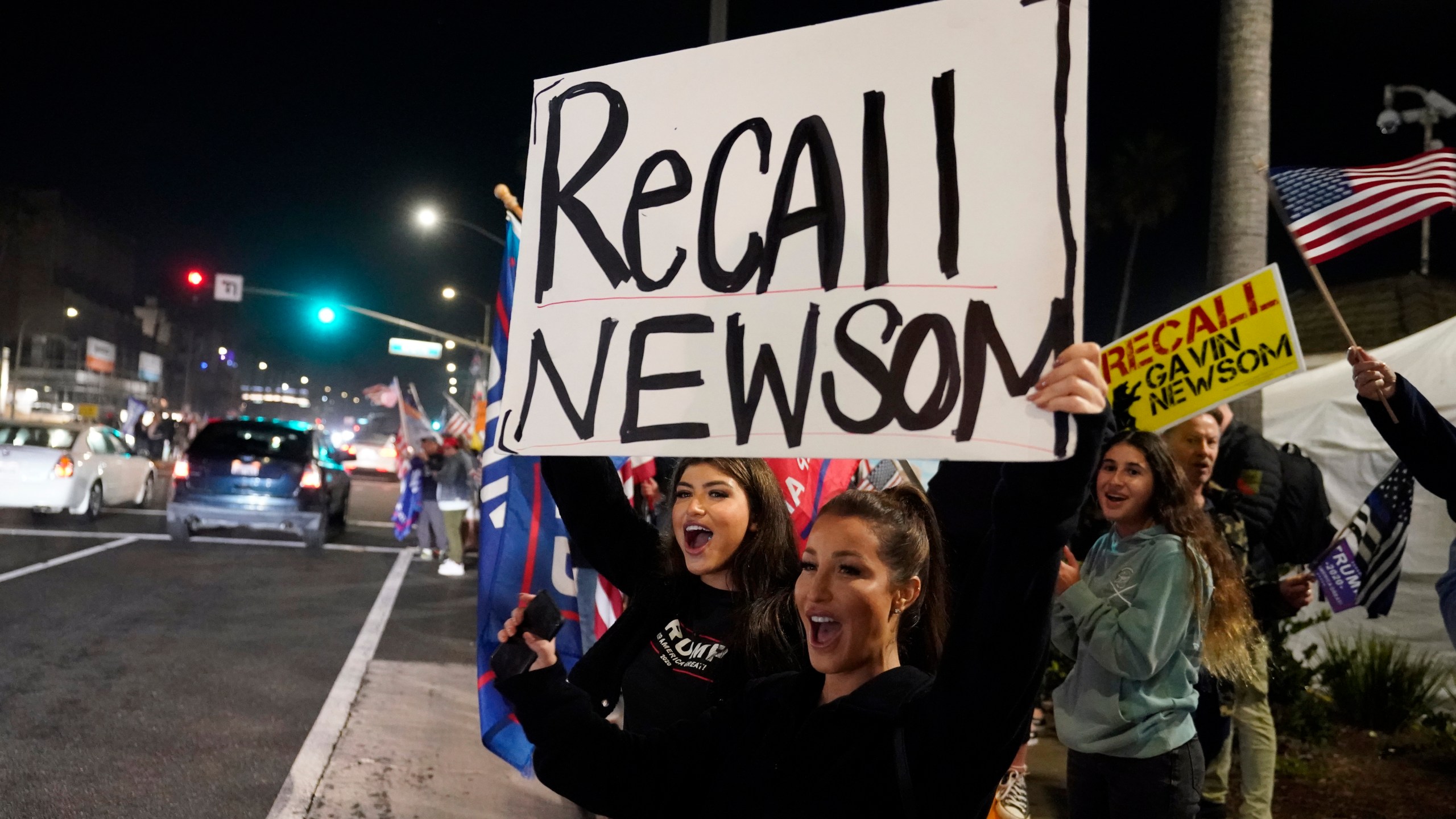 Demonstrators shout slogans while carrying a sign calling for a recall on Gov. Gavin Newsom during a protest in Huntington Beach against a stay-home order amid the COVID-19 pandemic on Nov. 21, 2020. (Marcio Jose Sanchez / Associated Press)