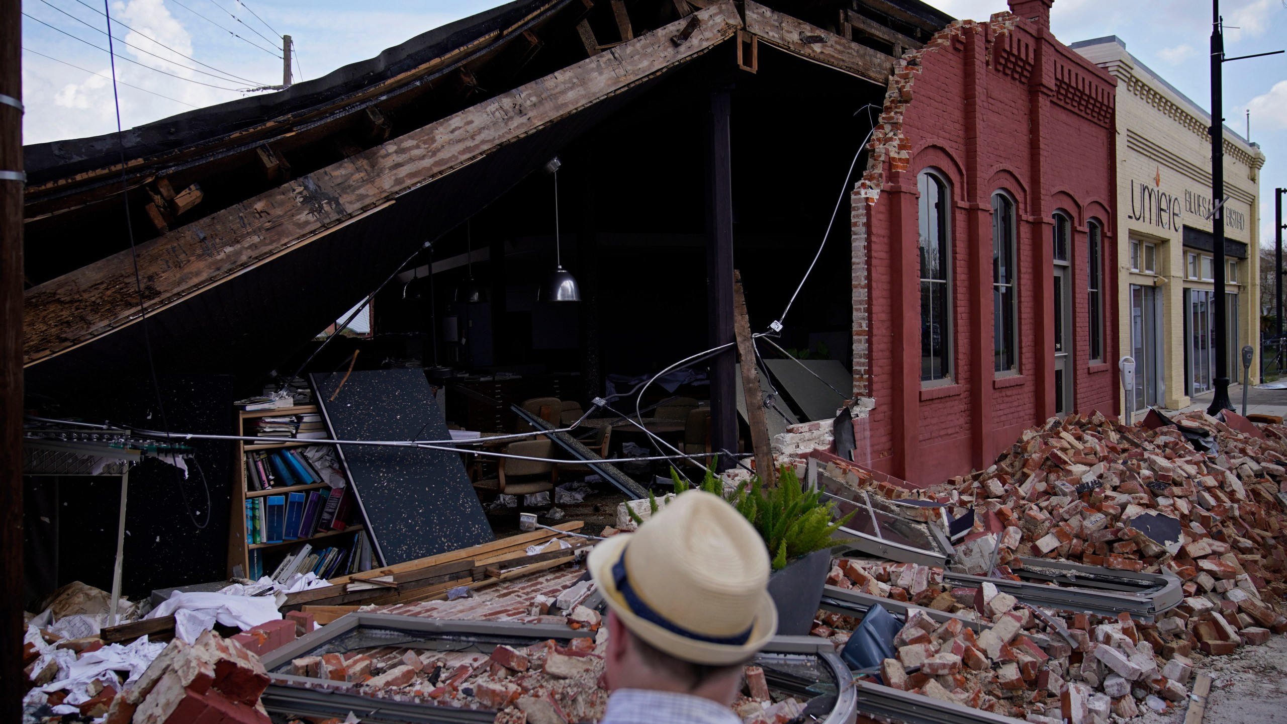 A man looks at a partially collapsed building in the aftermath of Hurricane Ida, Saturday, Sept. 4, 2021, in Houma, La. Full restoration of electricity to some of the hardest-hit areas of Louisiana battered by Hurricane Ida could take until the end of the month, the head of Entergy Louisiana warned Saturday. (AP Photo/John Locher)