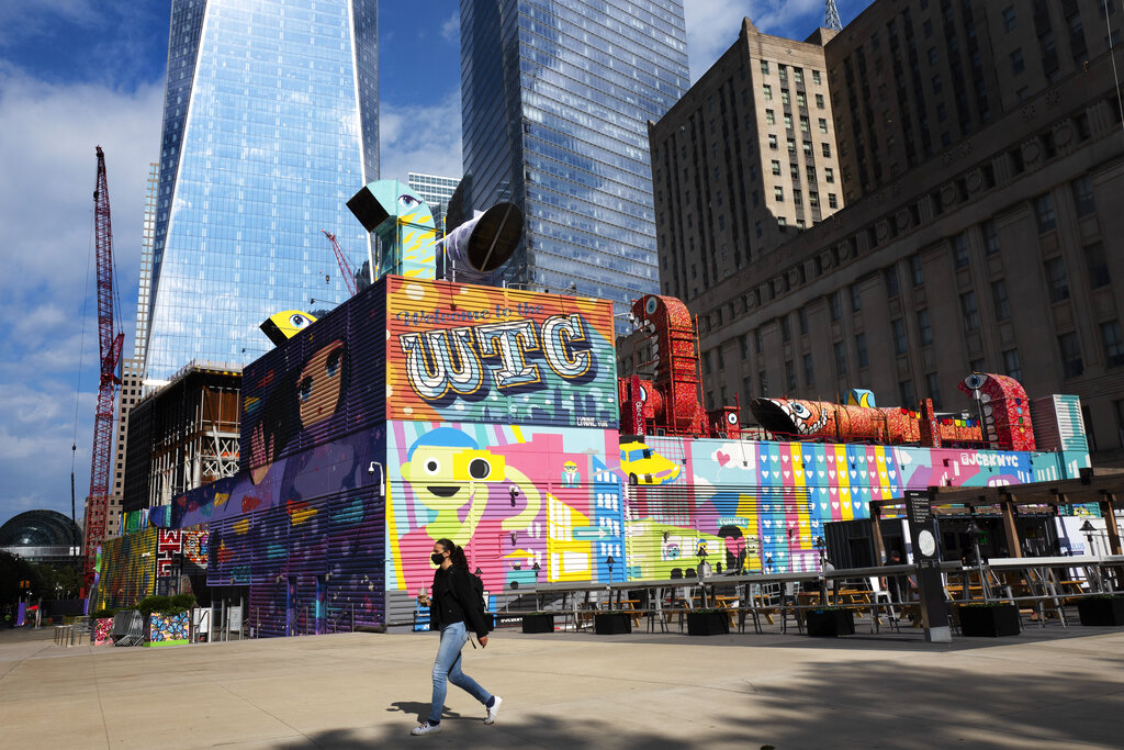 A woman walks by the colorful murals that surround the foundation for 2 World Trade Center, Wednesday, Sept. 8, 2021 in New York. (AP Photo/Mark Lennihan)