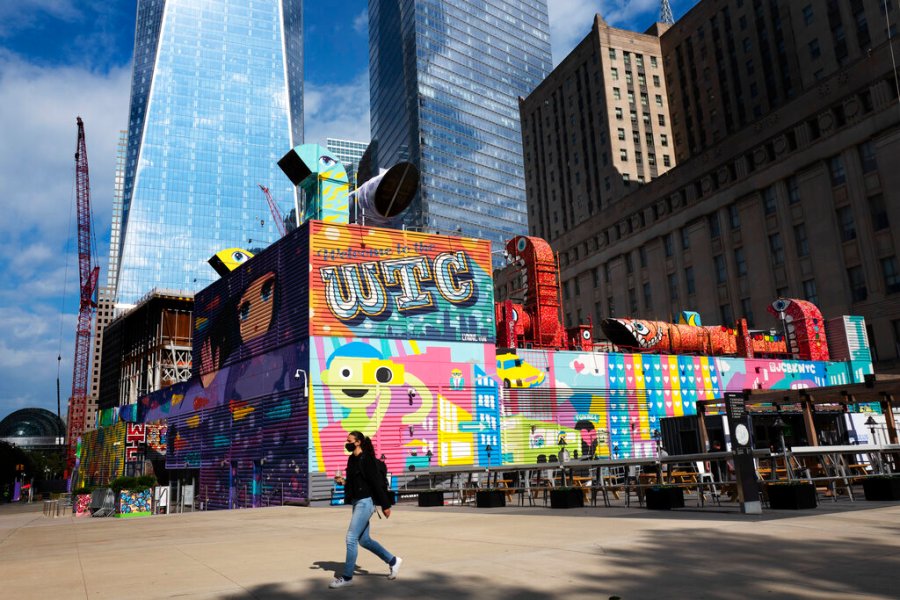 A woman walks by the colorful murals that surround the foundation for 2 World Trade Center, Wednesday, Sept. 8, 2021 in New York. (AP Photo/Mark Lennihan)