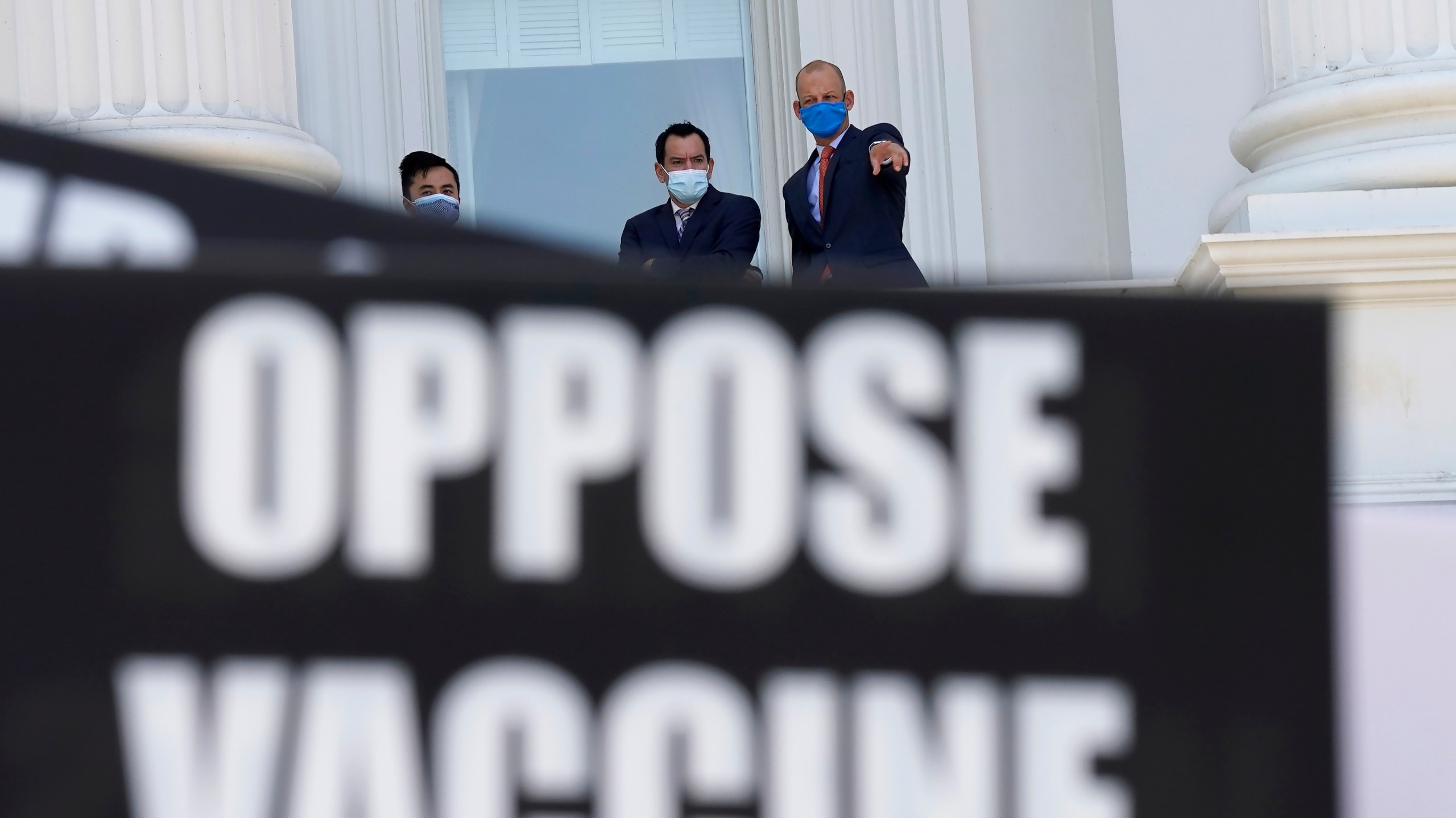 Assembly Speaker Anthony Rendon, of Lakewood, center, and Assemblyman Kevin McCarty, D-Sacramento, right, watch from the balcony outside the Assembly Chambers as protesters opposing vaccine mandates gather at the Capitol in Sacramento. (Rich Pedroncelli/Associated Press)