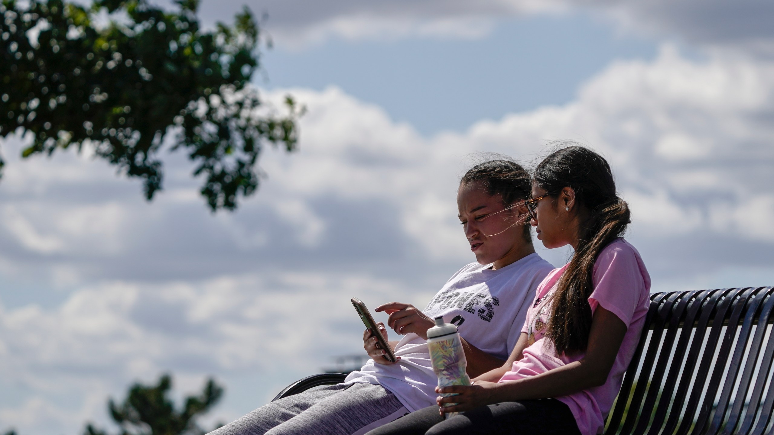 Savannah Brown and Glendy Stollberg use their phone in Kilbourn Reservoir Park Wednesday, Sept. 8, 2021, in Milwaukee. The City of Milwaukee has placed wireless broadband hotspots in the park during the pandemic. (AP Photo/Morry Gash)