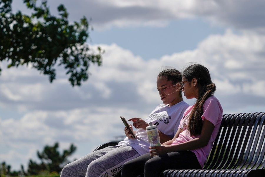 Savannah Brown and Glendy Stollberg use their phone in Kilbourn Reservoir Park Wednesday, Sept. 8, 2021, in Milwaukee. The City of Milwaukee has placed wireless broadband hotspots in the park during the pandemic. (AP Photo/Morry Gash)