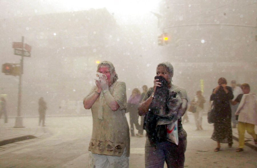 In this Sept. 11, 2001 file photo, people covered in dust from the collapsed World Trade Center buildings, walk through the area, in New York. (AP Photo/Suzanne Plunkett, File)