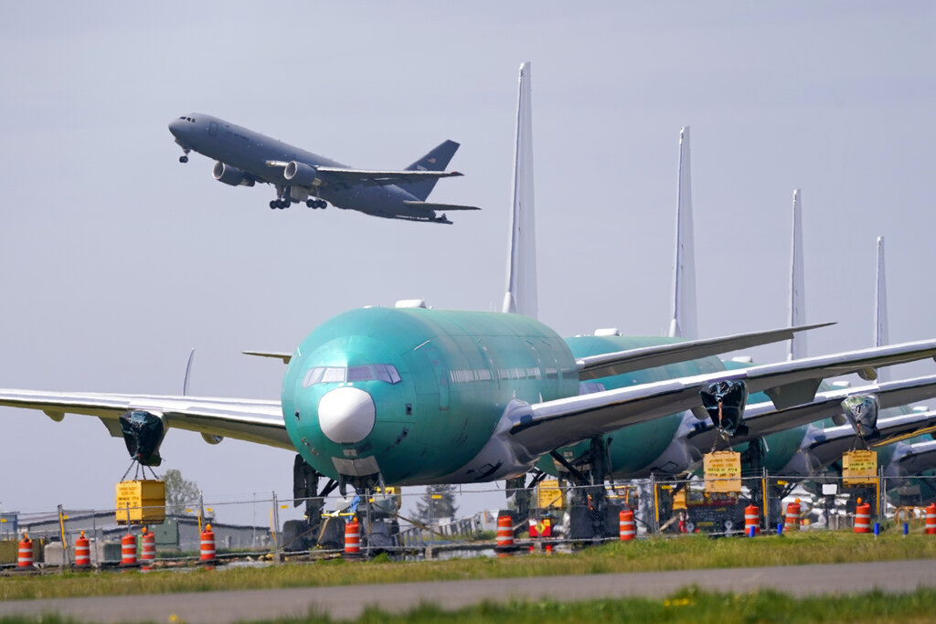 In this April 23, 2021 file photo, A U.S. Air Force KC-46A Pegasus jet takes off in view of a line of Boeing 777X jets parked nose to tail on an unused runway at Paine Field, near Boeing's massive production facility in Everett, Washington. (AP Photo/Elaine Thompson, File)