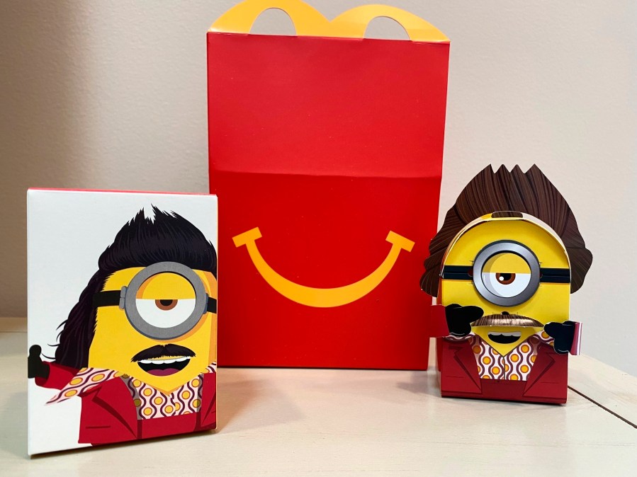 A cardboard McDonald’s Happy Meal toy is shown with a Happy Meal box on Sept. 20, 2021. McDonald’s plans to “drastically” reduce the plastic in its Happy Meal toys worldwide by 2025. The burger giant said Tuesday, Sept. 21 it’s working with toy companies to develop new ideas, such as three-dimensional cardboard superheroes kids can build or board games with plant-based or recycled game pieces. (AP Photo/Dee-Ann Durbin)