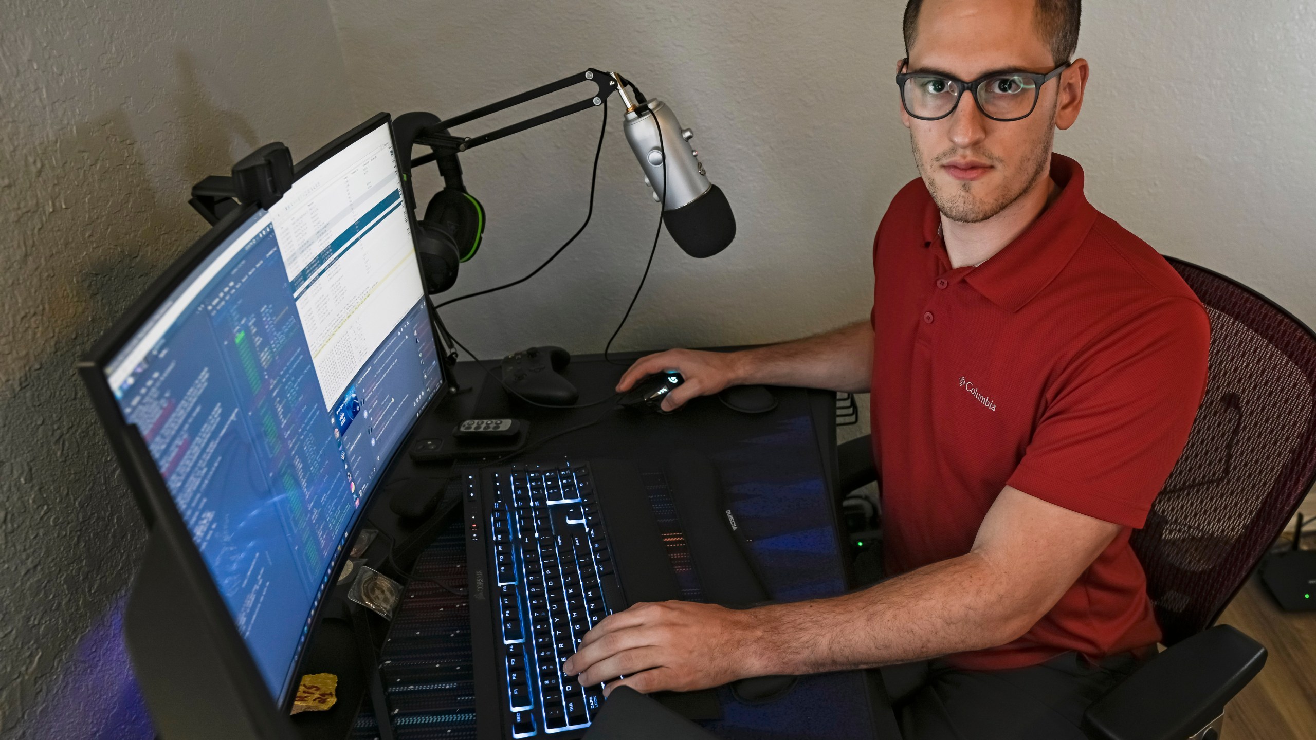 In this Sept. 20, 2021, photo Austin Moody poses for a photo as he sits a his home work station in Tampa, Fla. Moody, the Michigan native, got a scholarship from the Department of Defense that required working for the agency at least a year after graduating. (AP Photo/Steve Nesius)