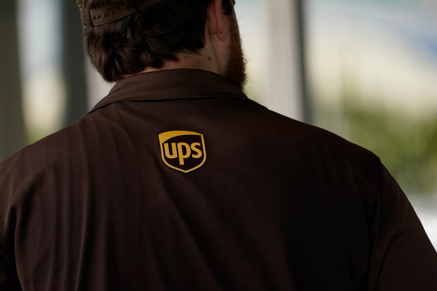 A UPS logo is on the shirt of a driver as he enters a United Parcel Service store with packages in Jackson, Miss., Monday, July 26, 2021. Amazon, Chobani, UPS and more than 30 other companies have vowed to hire and train refugees fleeing Afghanistan for the U.S. The companies said Tuesday, Sept. 21, that they want to help the tens of thousands of Afghan refugees coming to America to integrate into the economy. (AP Photo/Rogelio V. Solis, File)