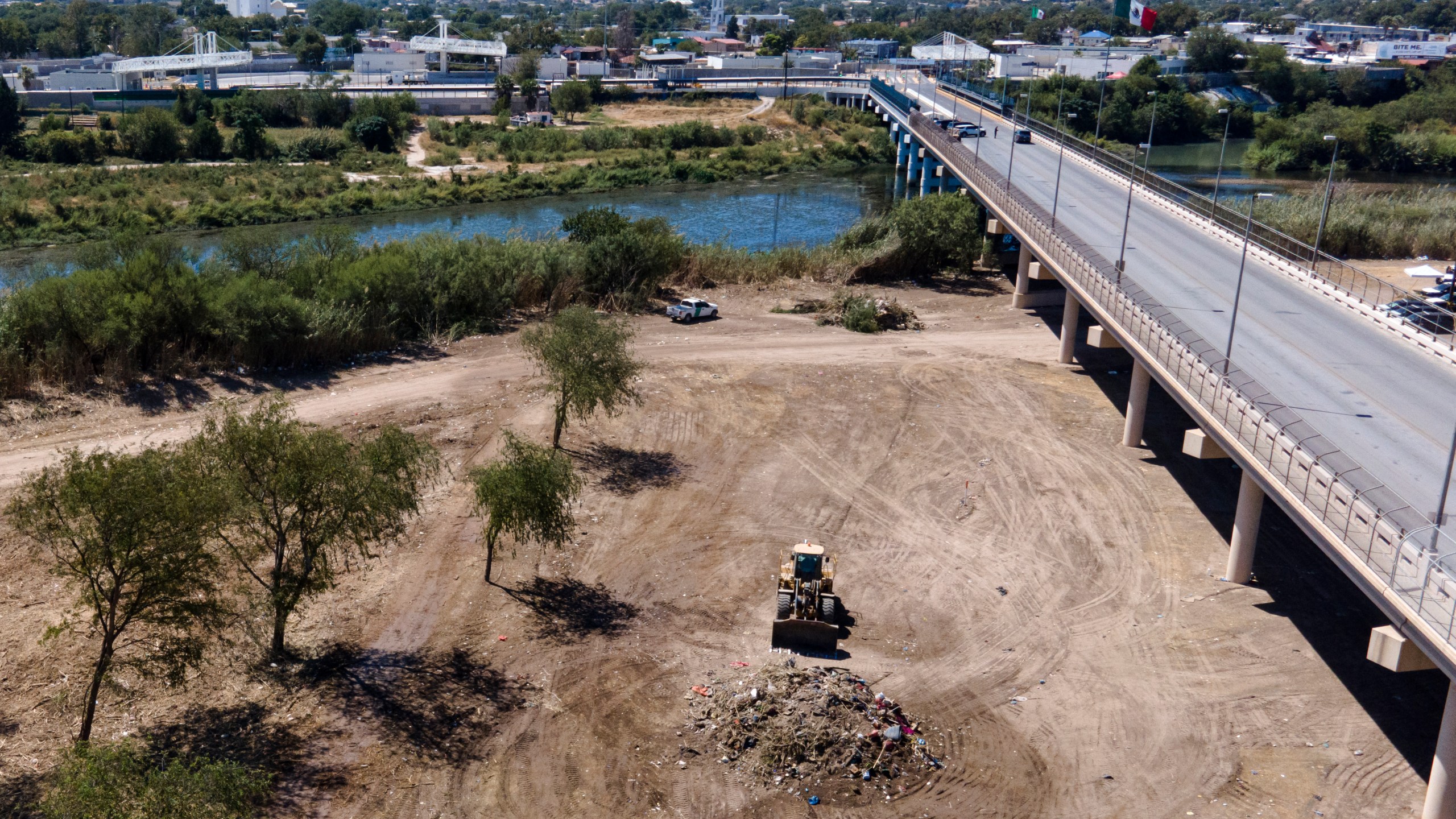 A bulldozer is seen next to a mound of debris while crews clear an area where migrants, many from Haiti, were encamped along the Del Rio International Bridge, Friday, Sept. 24, 2021, in Del Rio, Texas. (AP Photo/Julio Cortez)