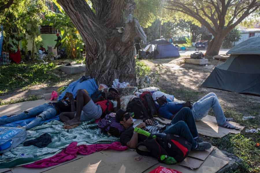 Migrants rest under the shade of a tree in Ciudad Acuna, Mexico, Friday, Sept. 24, 2021, across the Rio Grande from Del Rio, Texas. (AP Photo/Felix Marquez)