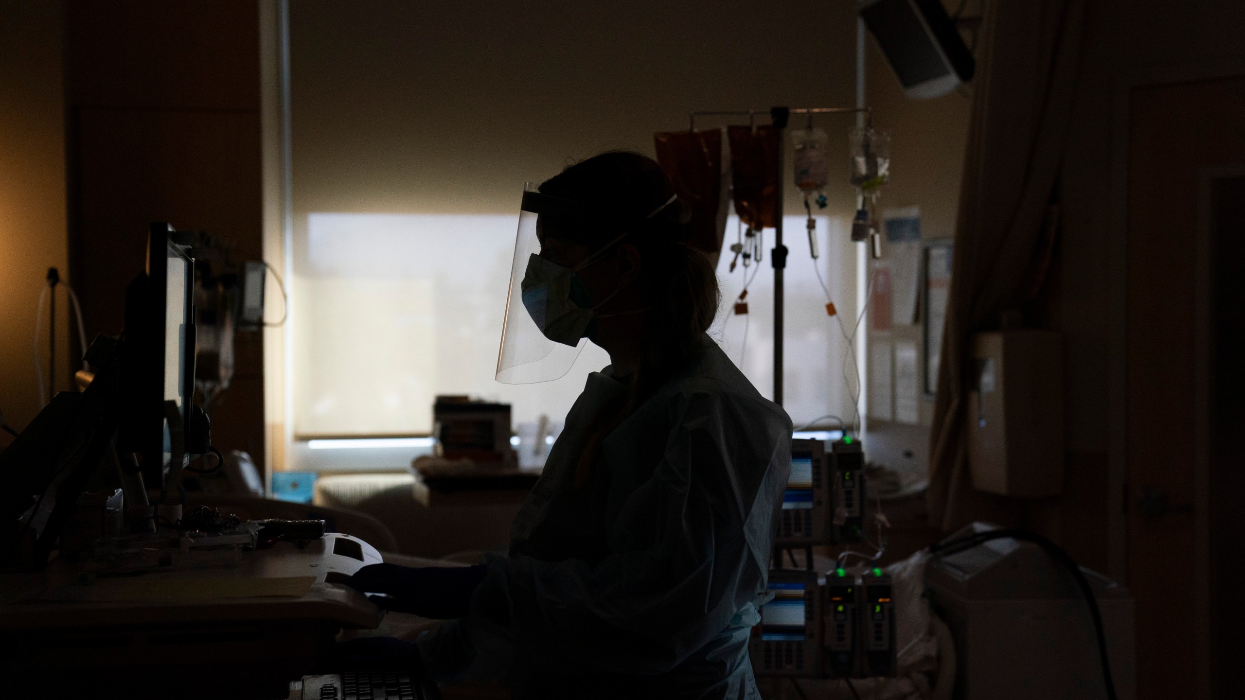 In this Nov. 19, 2020, file photo, a nurse works on a computer while assisting a COVID-19 patient at a hospital in Los Angeles. Across the country, doctors and nurses on the front lines of the coronavirus pandemic are dealing with hostility, threats and violence from patients angry over safety rules designed to keep the virus from spreading. (AP Photo/Jae C. Hong, File)