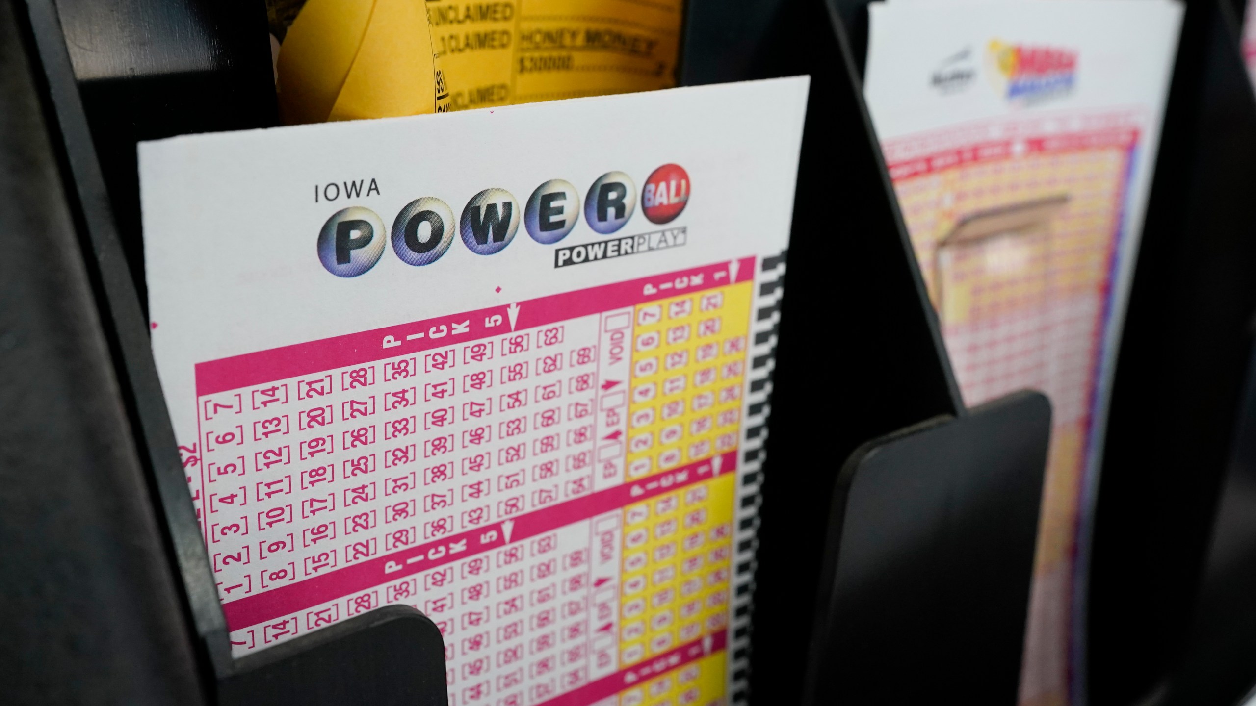 In this Jan. 12, 2021 file photo, blank forms for the Powerball lottery sit in a bin at a local grocery store, in Des Moines, Iowa. (AP Photo/Charlie Neibergall)