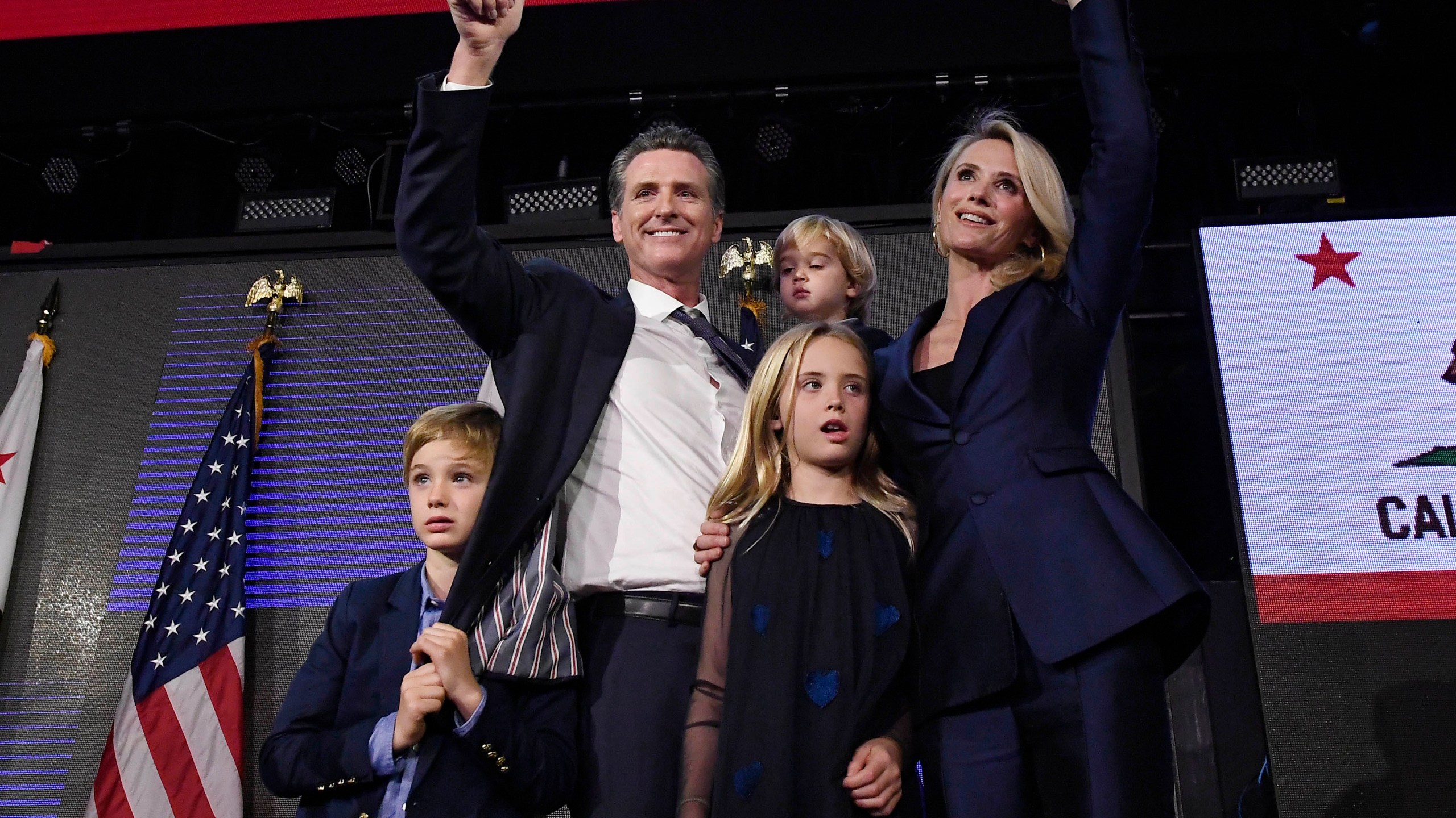 A newly elected Gov. Gavin Newsom holds his son Dutch, 2, and stands with his son Hunter, 7, wife Jennifer Siebel Newsom and daughter Montana, 9, as he waves to supporters during election night event in Los Angeles on Nov. 6, 2018. (Kevork Djansezian / Getty Images)