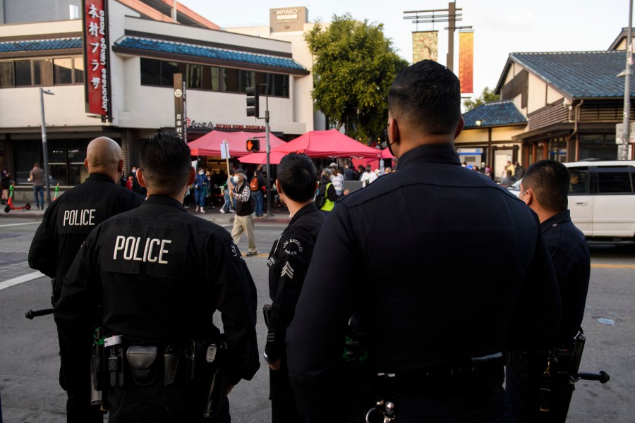 Los Angeles Police Department (LAPD) officers watch as a memorial procession for nursing home residents who died due to Covid-19 proceeds on March 20, 2021, in the Little Tokyo neighborhood of Los Angeles. (PATRICK T. FALLON/AFP via Getty Images)