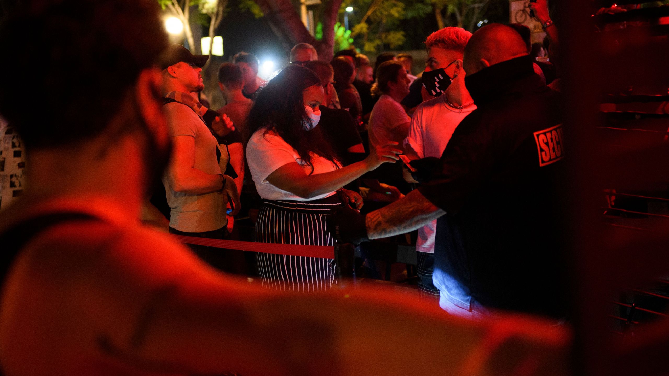 Customers are required by security to wear face masks to enter a bar in West Hollywood on July 18, 2021. (Patrick T. Fallon / AFP / Getty Images)