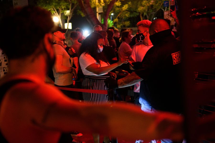 Customers are required by security to wear face masks to enter a bar in West Hollywood on July 18, 2021. (Patrick T. Fallon / AFP / Getty Images)