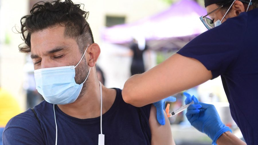 Juan Rodriguez, left, reacts while receiving Johnson & Johnson's Janssen COVID-19 vaccine administered by vocational nurse Christina Garibay at a Skid Row community outreach event in Los Angeles on Aug. 22, 2021. (Frederic J. Brown / AFP / Getty Images)