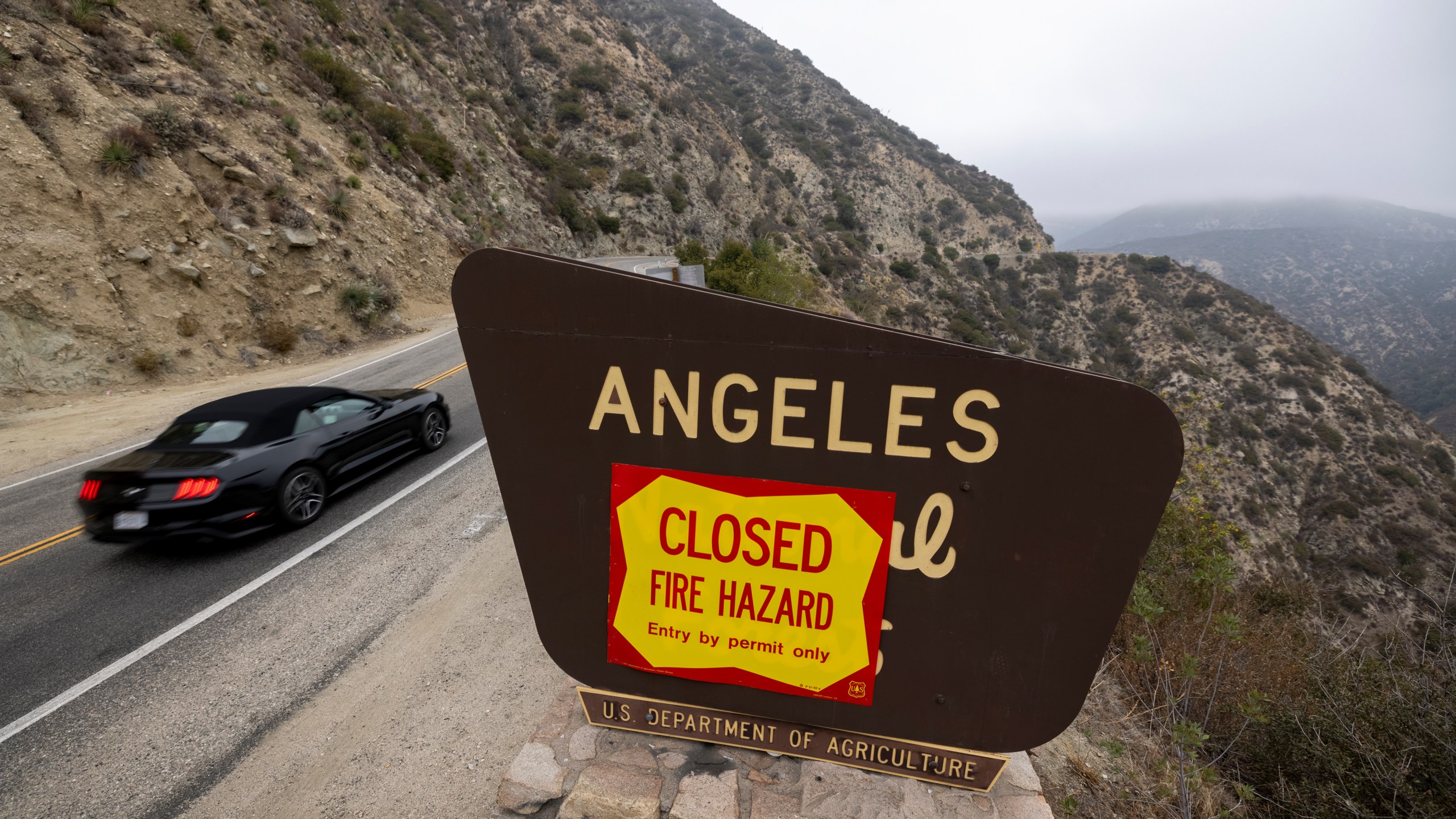 A motorcyclist passes forest closure signage along the Angeles Crest Highway in the Angeles National Forest on Sept. 2, 2021, near La Canada Flintridge, California. (David McNew/Getty Images)