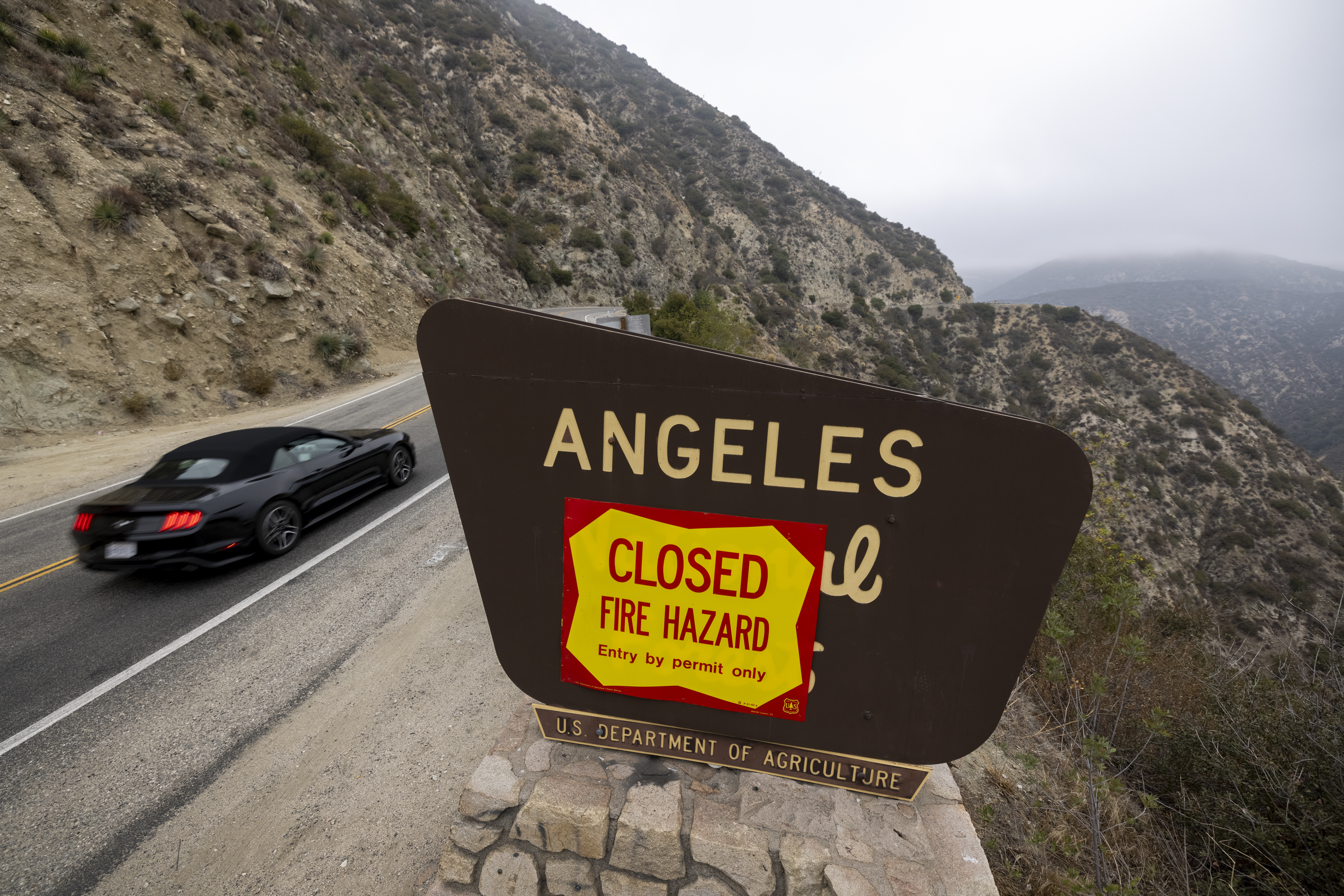 A motorcyclist passes forest closure signage along the Angeles Crest Highway in the Angeles National Forest on Sept. 2, 2021, near La Canada Flintridge, California. (David McNew/Getty Images)