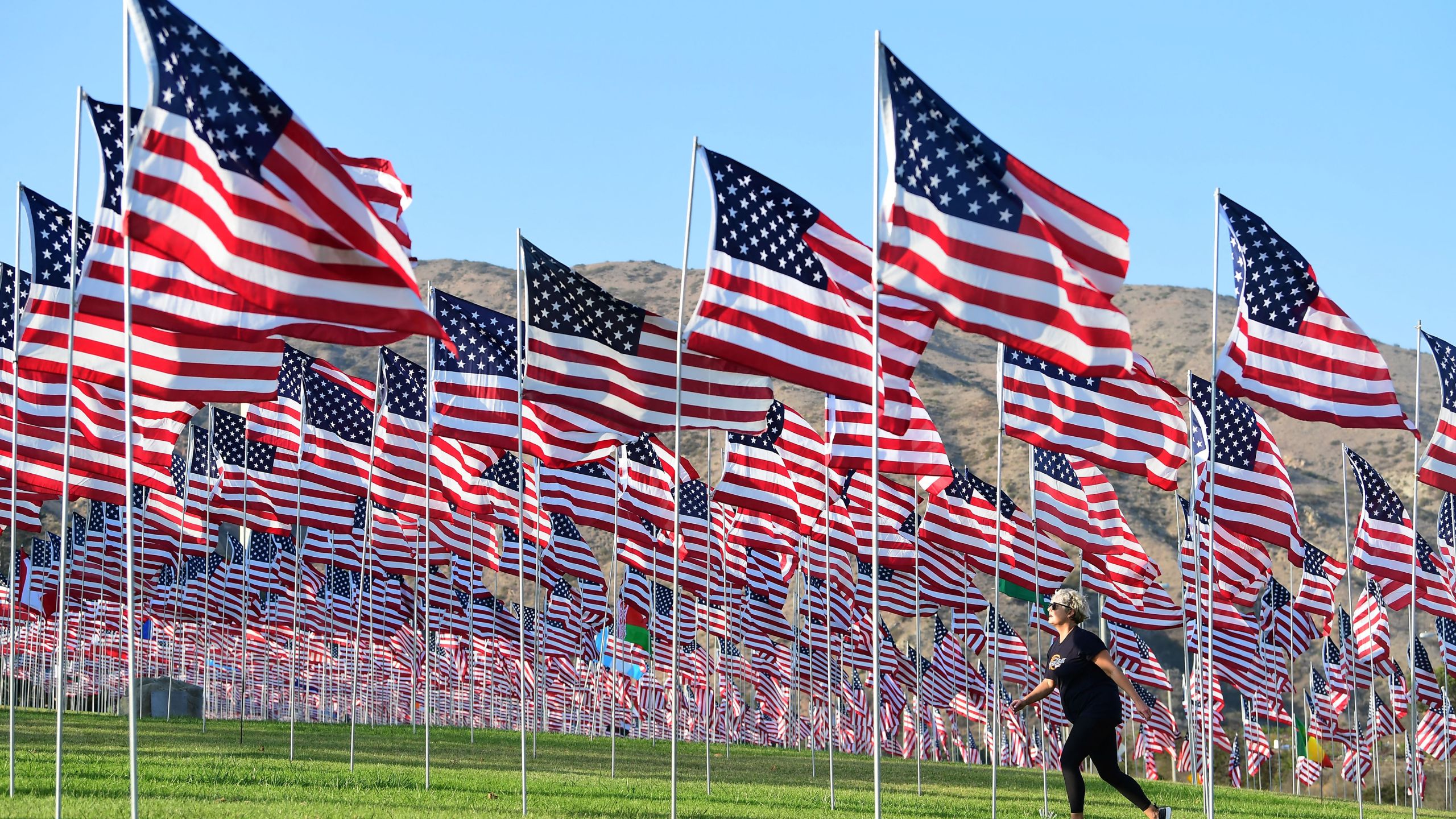 A woman walks past a display of U.S. flags to commemorate the 20th anniversary of 9/11 with the annual Waves of Flags display and remembrance at Pepperdine University in Malibu, California on Sept. 8, 2021. (FREDERIC J. BROWN/AFP via Getty Images)