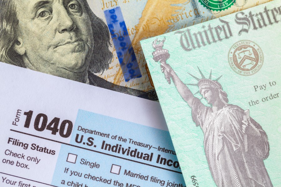 A tax refund check is seen on top of Form 1040 and a $100 bill. (iStock/Getty Images Plus)