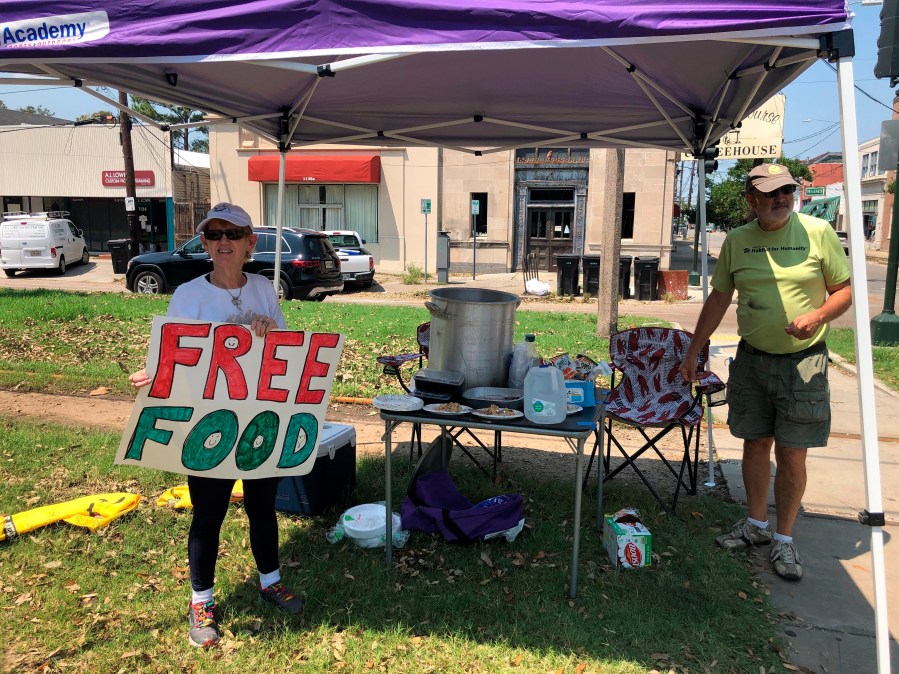 Joyce and Dave Thomas offer free jambalaya, cooked up by one of their neighbors, along the Carrollton streetcar tracks in New Orleans on Thursday, Sept. 2, 2021. Much of the city was without power and many restaurants and individuals were trying to help the community with free food. (AP Photo/Kevin McGill)