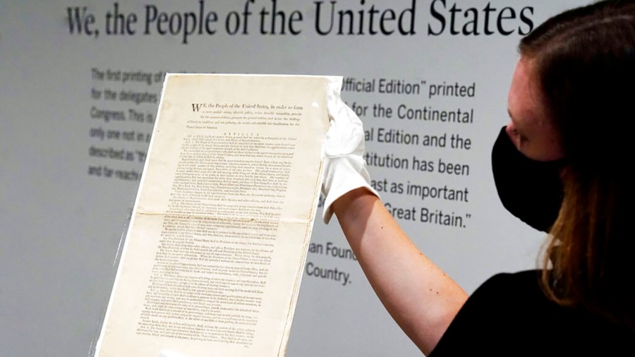 Ella Hall, a specialist in Books and Manuscripts at Sotheby's, in New York, holds a 1787 printed copy of the U.S. Constitution, Friday, Sept. 17, 2021. Sotheby's announced Friday — appropriately on Constitution Day — that in November it will put up for auction one of just 11 surviving copies of the Constitution from the official first printing produced for the delegates to the Constitutional Convention and for the Continental Congress. It's the only copy that remains in private hands and has an estimate of $15 million-$20 million. (AP Photo/Richard Drew)