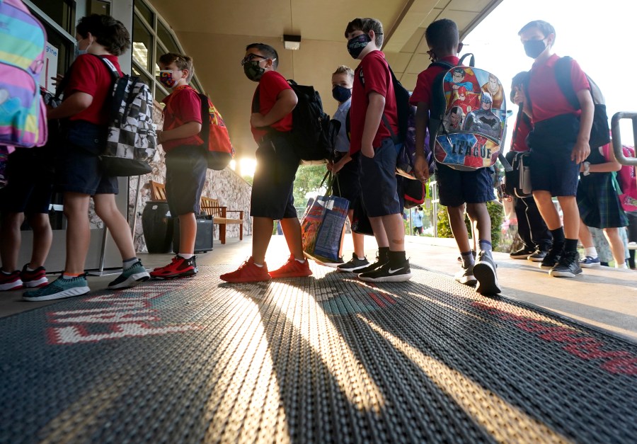 Wearing masks to prevent the spread of COVID-19, elementary school students line up to enter school for the first day of classes in Richardson, Texas, Tuesday, Aug. 17, 2021. (AP Photo/LM Otero)