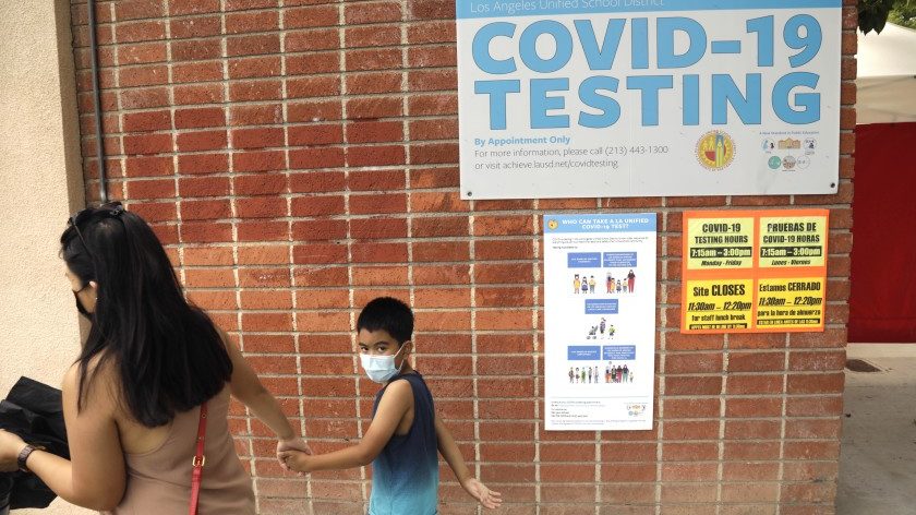 A student and parent walk past a sign advertising COVID-19 testing on an Los Angeles Unified School District campus in this undated photo. (Genaro Molina / Los Angeles Times)