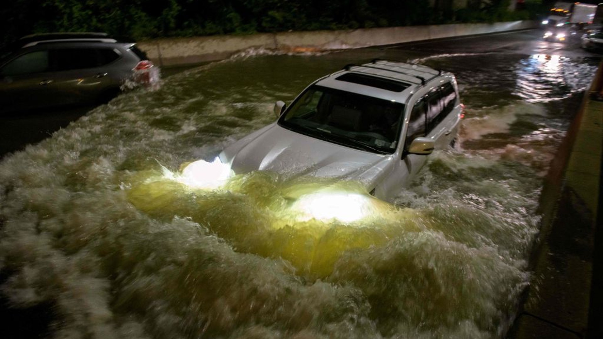 A motorist drives a car through a flooded expressway in Brooklyn, New York early on September 2, 2021, as flash flooding and record-breaking rainfall brought by the remnants of Storm Ida swept through the area. ( ED JONES/AFP via Getty Images)