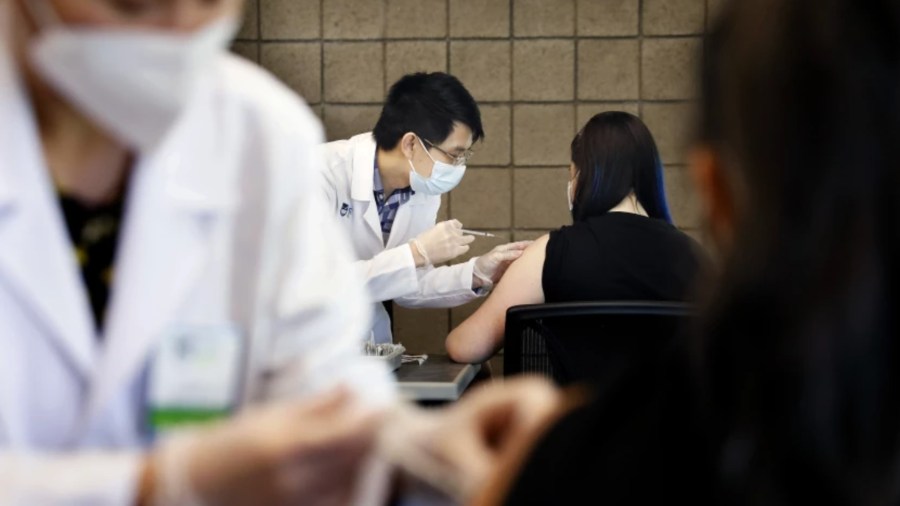 Sarith Mey, center, a pharmacist graduat intern with Rite Aid, administers a shot to CSUDH student Fritzi Bui, during a COVID-19 vaccination clinic hosted by Cal State Dominguez Hills in Carson.(Christina House/Los Angeles Times)