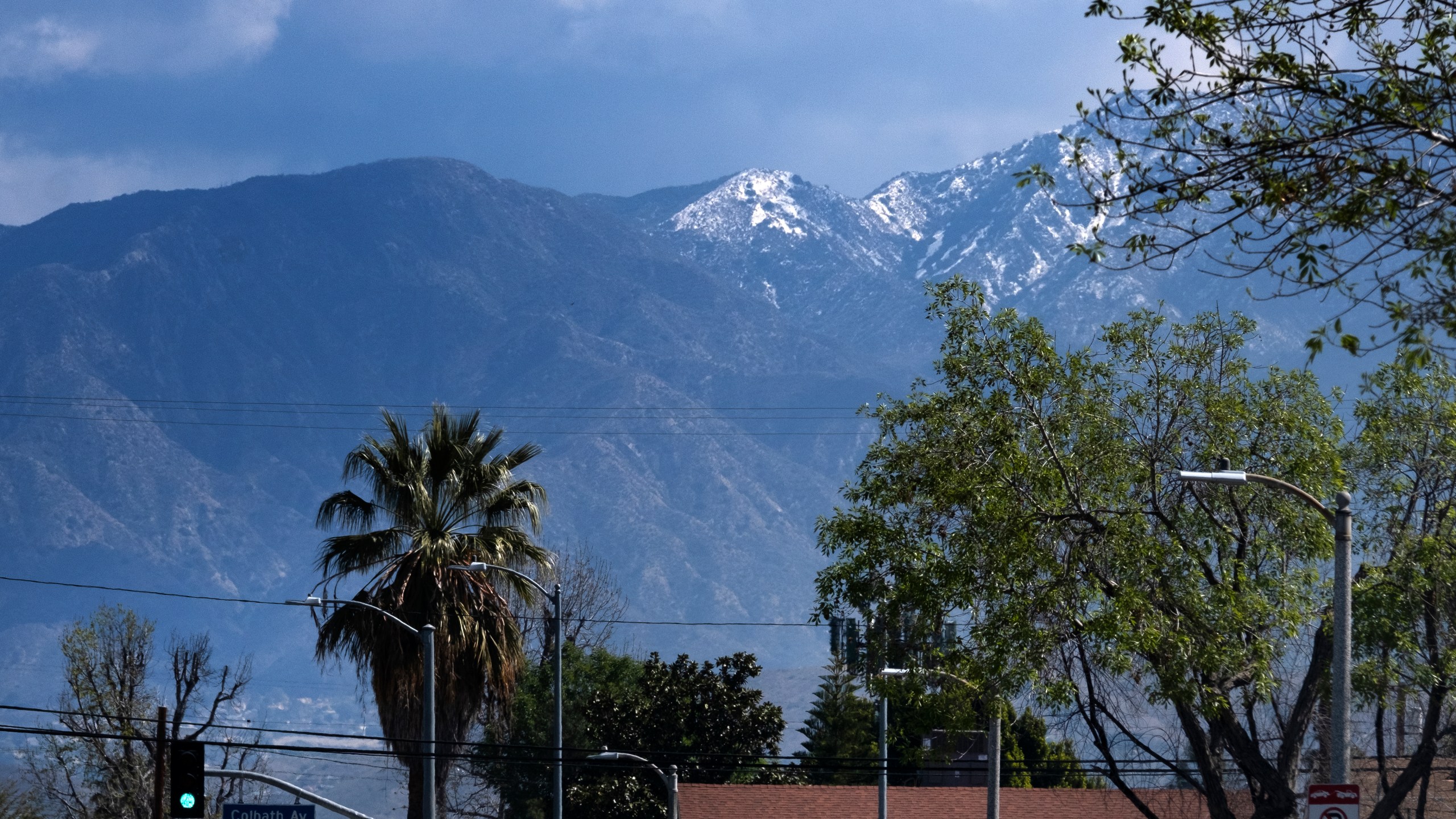 A lightly dusted snow capped hilltop is seen behind palm trees in the San Fernando Valley section of Los Angeles on March 12, 2021. (AP Photo/Richard Vogel)