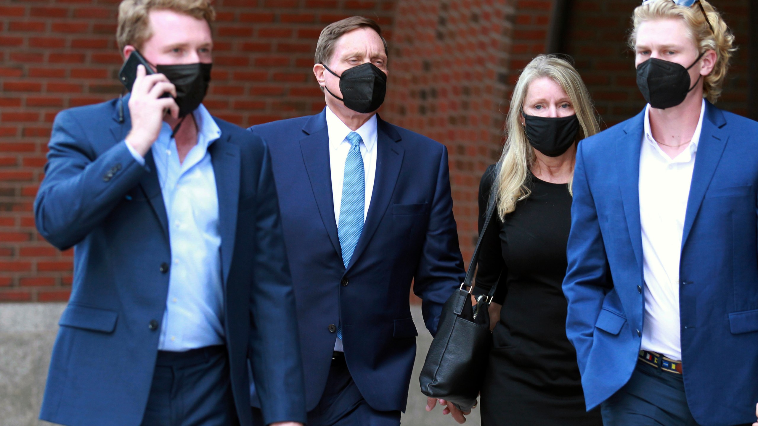 John Wilson, second left, holds his wife's hand, second right, as he leaves the John Joseph Moakley Federal Courthouse after the first day of his trial in the college admissions scandal on Sept.13, 2021, in Boston. (AP Photo/Stew Milne)